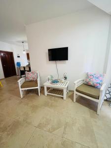a living room with two chairs and a tv on the wall at Lovely Beachfront 2 bedrooms condo with 2 pools in Las Terrenas