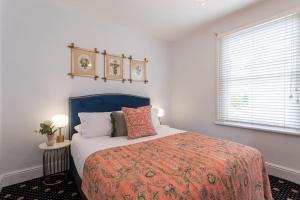 a bedroom with a bed with an orange blanket and a window at Two Worlds Townhouse in Launceston