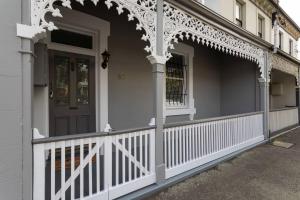 a white porch with a white fence and a door at Two Worlds Townhouse in Launceston