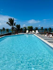 uma piscina com cadeiras e o oceano ao fundo em Lovely Beachfront 2 bedrooms condo with 2 pools em Las Terrenas