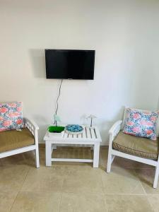 a living room with two chairs and a tv on a wall at Lovely Beachfront 2 bedrooms condo with 2 pools in Las Terrenas
