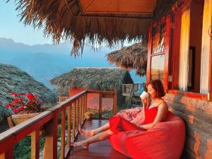 a woman in a red dress sitting on a balcony at Sapa Rosie House in Sa Pa