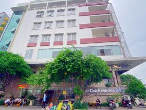 un edificio blanco alto con gente sentada frente a él en Sen Trang Hotel, en Lào Cai