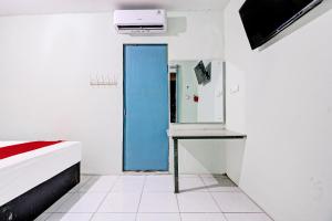 um quarto com uma porta azul, uma mesa e um espelho em OYO Life 92032 Utama Hotel & Karaoke em Trenggalek