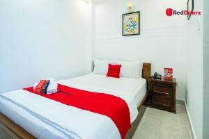 um quarto com uma cama vermelha e branca e uma mesa de cabeceira em The Sun Hotel em Ho Chi Minh