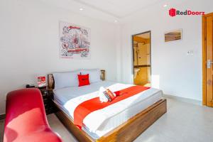 um quarto com uma cama e uma cadeira vermelha em The Sun Hotel em Ho Chi Minh