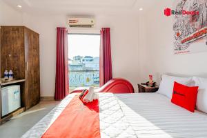 a bedroom with a bed with a red chair and a window at The Sun Hotel in Ho Chi Minh City