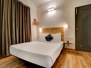 a bedroom with a large white bed and a window at Upar Hotels Indiranagar in Bangalore