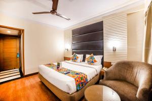um quarto de hotel com uma cama e uma cadeira em FabHotel BMK Grand em Nova Deli
