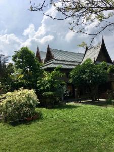 una casa con un patio verde con árboles y arbustos en MrT Riverside Sampran มิสเตอร์ที โฮมสเตย์-ช้องนาง, en Sam Phran
