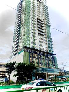 een hoog gebouw met een auto ervoor geparkeerd bij Across Sm City Cebu Sunvida Tower Studio Unit in Cebu City