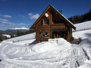 una cabaña de madera en la nieve con un montón de nieve en Gerstbreinhütte en Bad Sankt Leonhard im Lavanttal