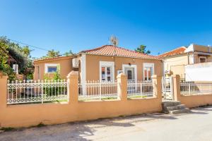 a yellow house with a white fence at Villa Pines in Limenaria