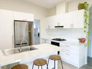 a kitchen with white cabinets and a sink and stools at Quiet Private Nimbin Townhouse in Nimbin