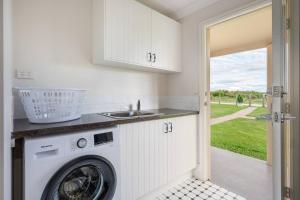 a kitchen with a washing machine and a sink at 'Vineyard Cottage' A Golden Escape among the Vines in Eurunderee