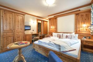 a bedroom with a large bed and a table at Hotel Gianna in Madonna di Campiglio