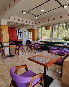 un restaurante con sillas moradas, mesas y ventanas en Soke Boutique Homestay en Gangtok