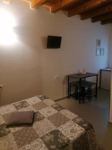 - une chambre avec un lit, une table et une télévision dans l'établissement A New Guesthouse, à Pavia