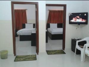 a bedroom with two beds and a tv and mirrors at Al Basateen Hotel Apartment in Sur