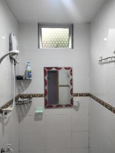 Baño blanco con espejo y ventana en Taman Tunku Miri Budget Homestay, en Miri