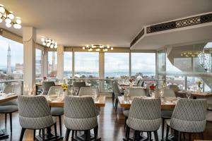イスタンブールにあるアダマル ホテルのテーブルと椅子、大きな窓のあるレストラン