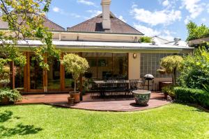 North Adelaide Heritage Cottages & Apartments في أديلايد: منزل به فناء وساحة بها عشب