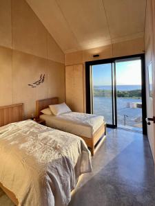 two beds in a room with a view of the water at Native Dog Cabin in Bremer Bay