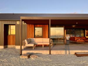 a house with a patio with a couch and windows at Native Dog Cabin in Bremer Bay