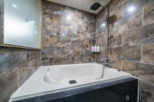 ein Badezimmer mit einer großen Badewanne und einem Spiegel in der Unterkunft Boutique Hotel XYM in Suwon