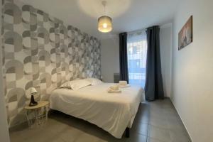 a bedroom with a white bed and a large window at Cosy apartment with balcony in the heart of Caen in Caen