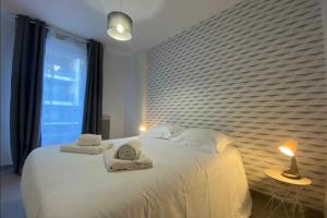 a bedroom with a white bed with towels on it at Cosy apartment with balcony in the heart of Caen in Caen