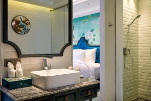 a bathroom with a white sink and a bedroom at Hoi An Delicacy Hotel & Spa in Hoi An