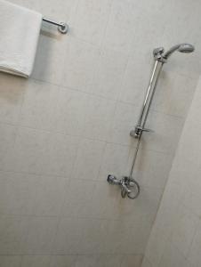 La salle de bains est pourvue d'une douche et d'un mur en carrelage blanc. dans l'établissement Al Basateen Hotel Apartment, à Sour