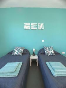 2 camas en una habitación con paredes azules en Villa Verano Apartamentos Compartidos Villaverde, en La Oliva