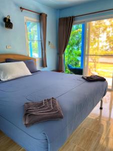 a blue bed with a towel on top of it at Twocans Resort KohMak - SHA in Ko Mak