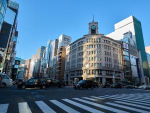 Tabist Ginza في طوكيو: شارع المدينة مزدحم بالسيارات والمبنى
