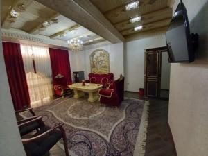 a living room with chairs and a table and a tv at EDEM Plaza in Bukhara