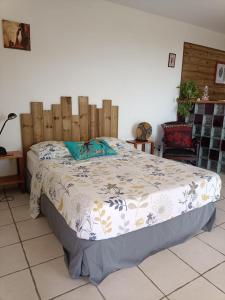 1 dormitorio con 1 cama con cabecero de madera en grand studio en bas de villa avec vue sur mer au Carbet, en Le Carbet