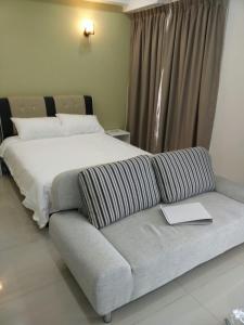 a bedroom with a bed and a couch with a book on it at DELUXE HOMESTAY @ D PERDANA in Kota Bharu