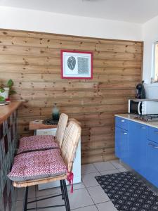 cocina con paredes de madera, mesa y silla en grand studio en bas de villa avec vue sur mer au Carbet en Le Carbet