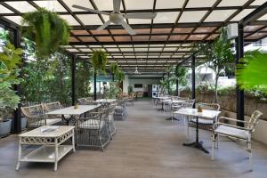 un restaurante con mesas, sillas y plantas en Abloom Exclusive Serviced Apartments, en Bangkok