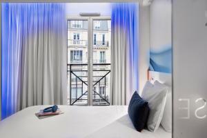 um quarto com uma cama branca e uma janela em Mercure Paris Gare du Nord em Paris
