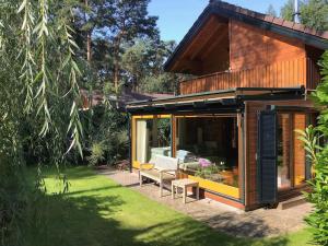 uma pequena casa com um pátio e um jardim em Houten chalet/bungalow in het bos, sauna, jacuzzi em Meijel