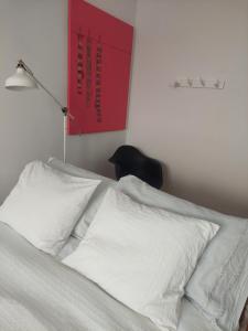 a bed with white sheets and a red sign on the wall at GALLE - Apartamento dos Infantes in Beja