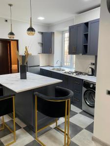 uma cozinha com armários azuis e uma ilha de cozinha com cadeiras pretas em Vernatoon Guest House em Vagharshapat