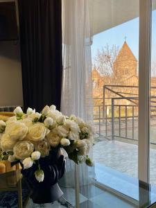 un jarrón lleno de rosas blancas sentadas en una mesa de cristal en Vernatoon Guest House, en Vagharshapat