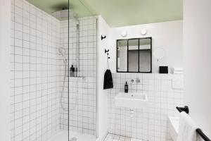 a white tiled bathroom with a shower and a sink at ibis Styles Amiens Centre in Amiens