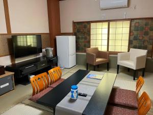 a living room with a table and chairs and a television at Kyoto Ryokan Gion Sano in Kyoto