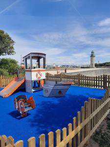 une aire de jeux avec un toboggan et un bateau au sol dans l'établissement Residence Hotel de la Plage, à Saint-Gilles-Croix-de-Vie