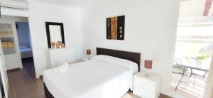 Apartamento Los Mares by DENIA COSTA في دينيا: غرفة نوم بيضاء مع سرير أبيض وطاولة